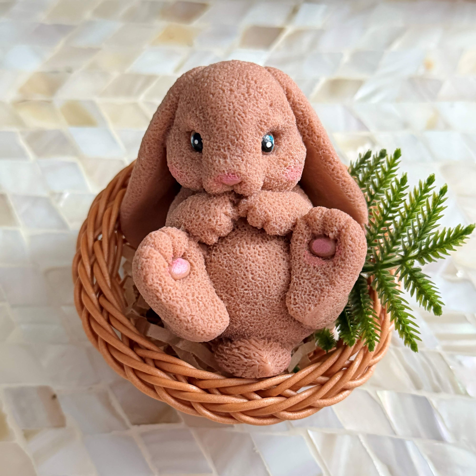 Plush bunny toy in a woven basket on a textured surface
