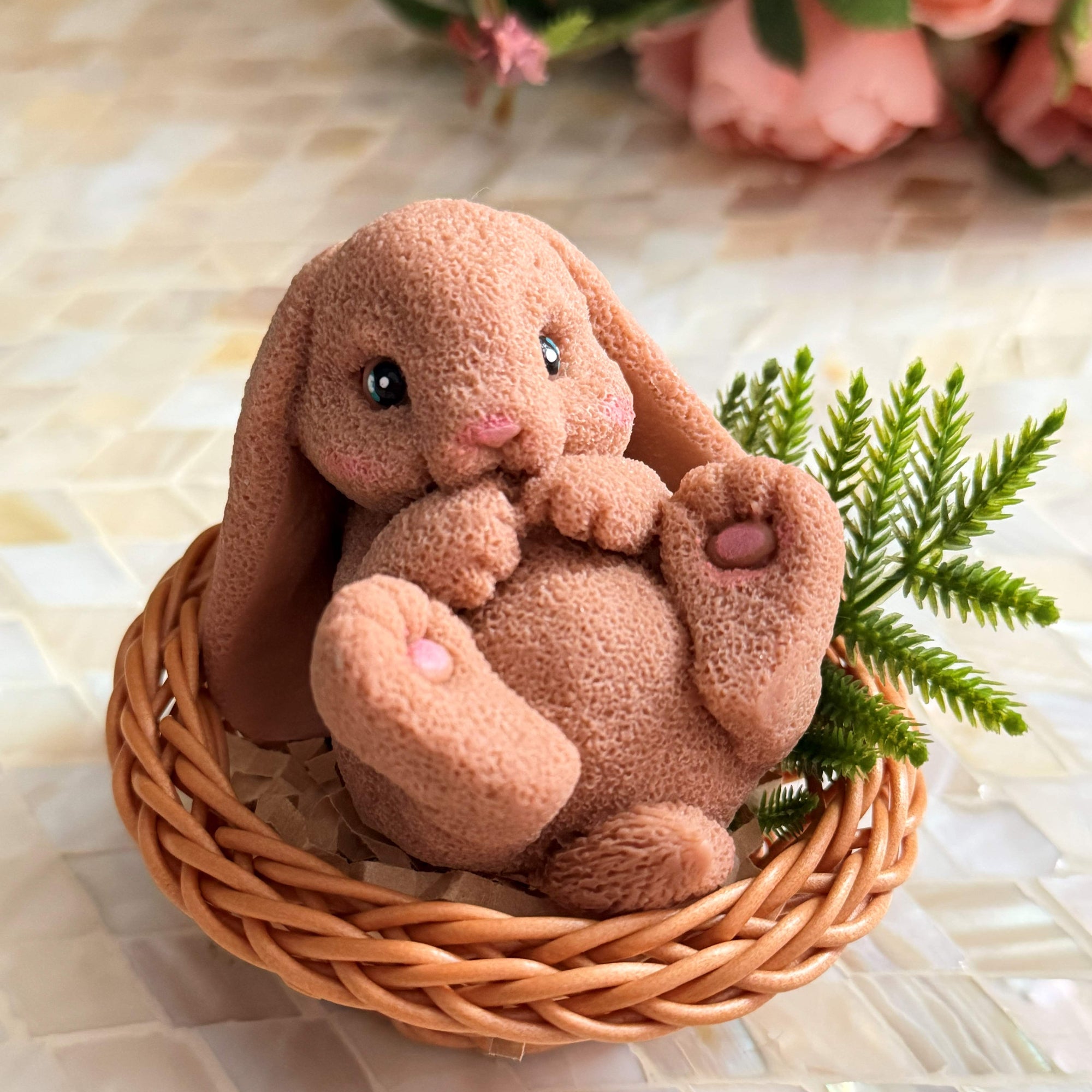 Plush bunny toy in a woven basket with flowers in the background