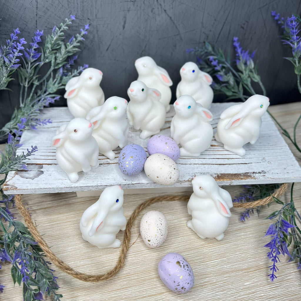 White ceramic bunnies and Easter eggs on a wooden surface with lavender decorations.