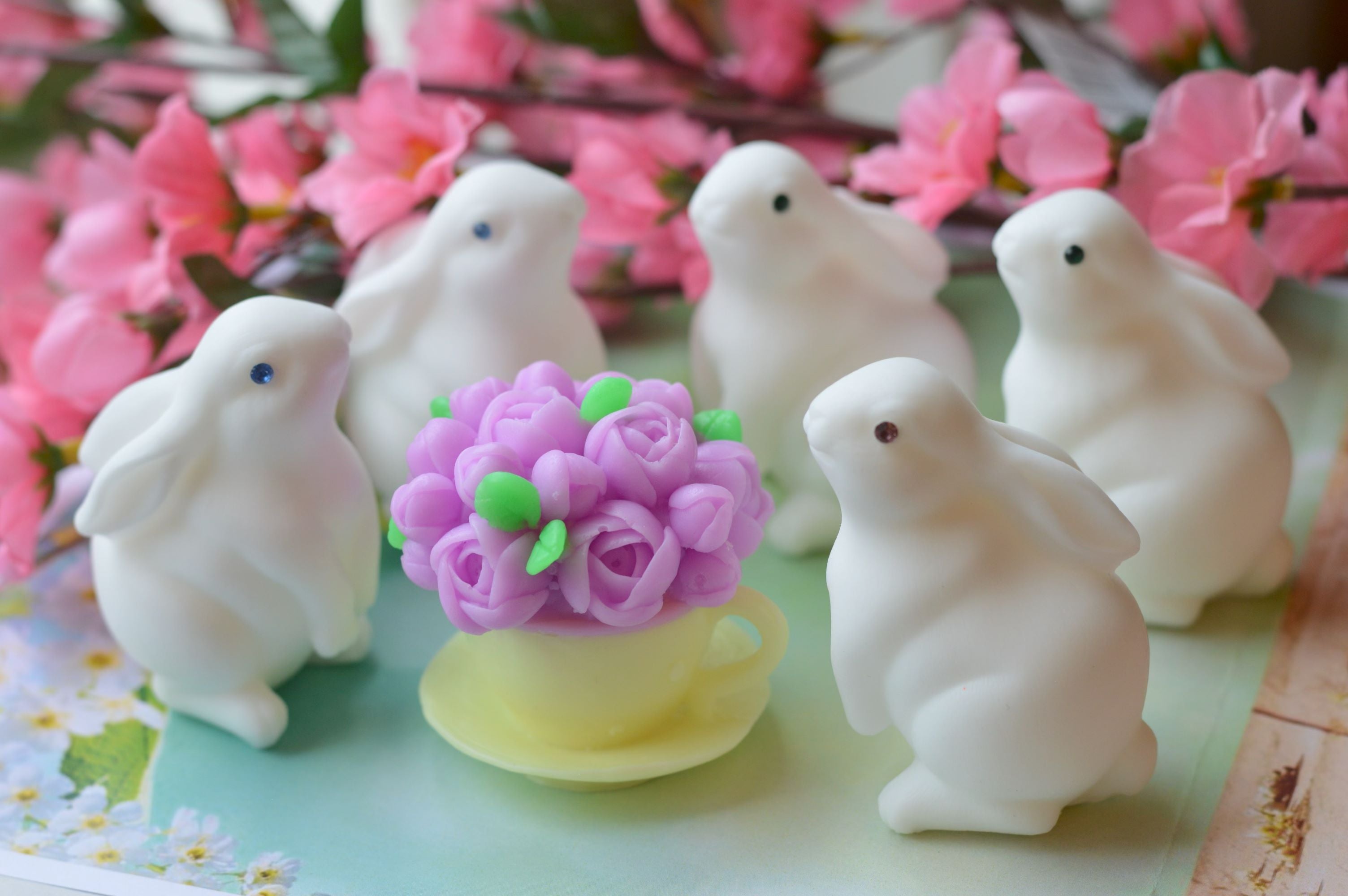 White rabbit figurines with a purple flower on a decorative background