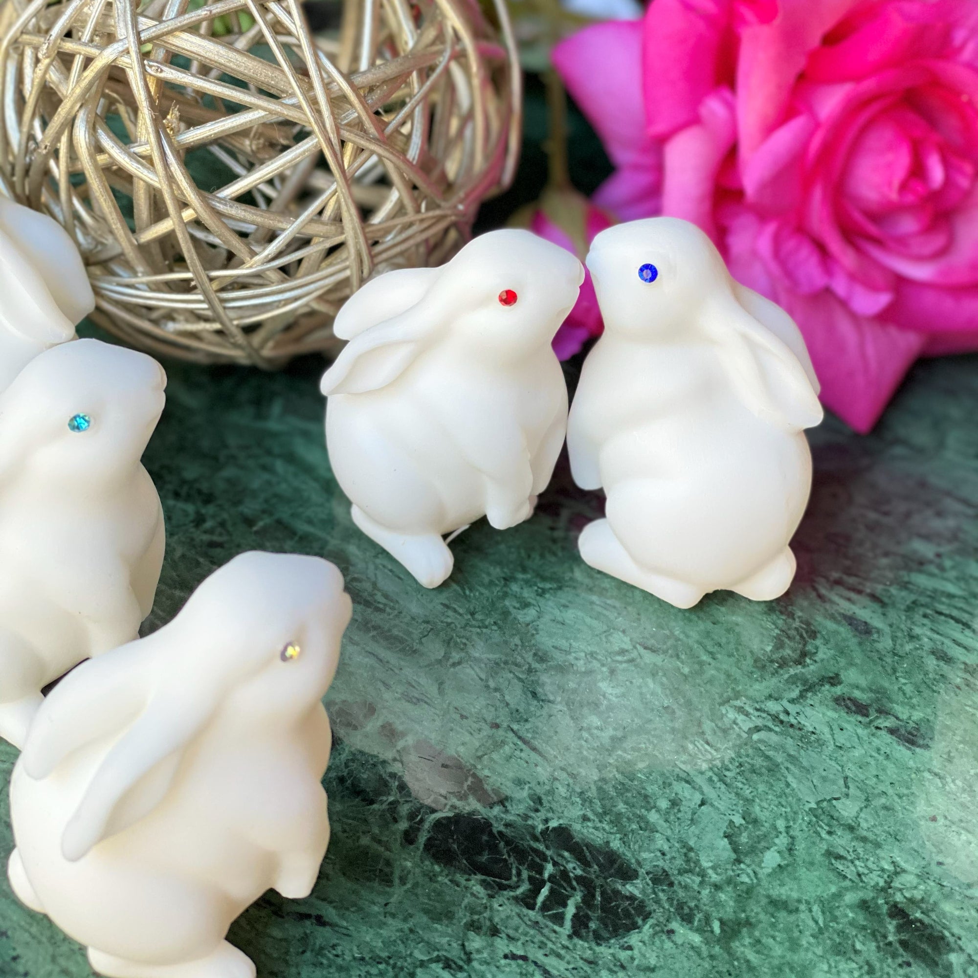 White rabbit figurines with colored eyes on a green surface with decorative elements.