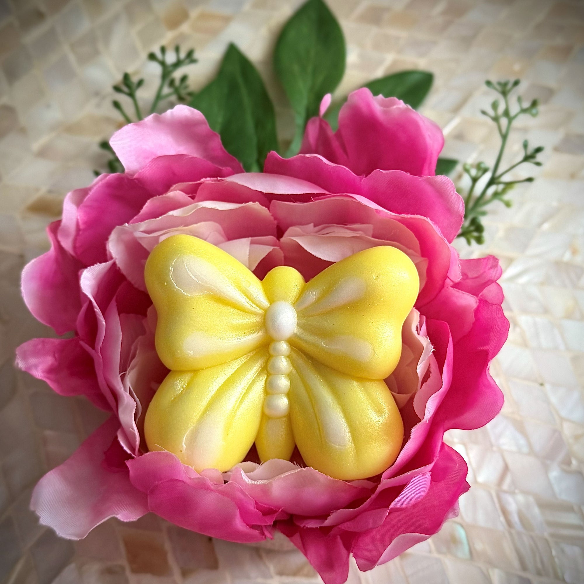 Pink flower with a yellow butterfly-shaped object on a textured surface