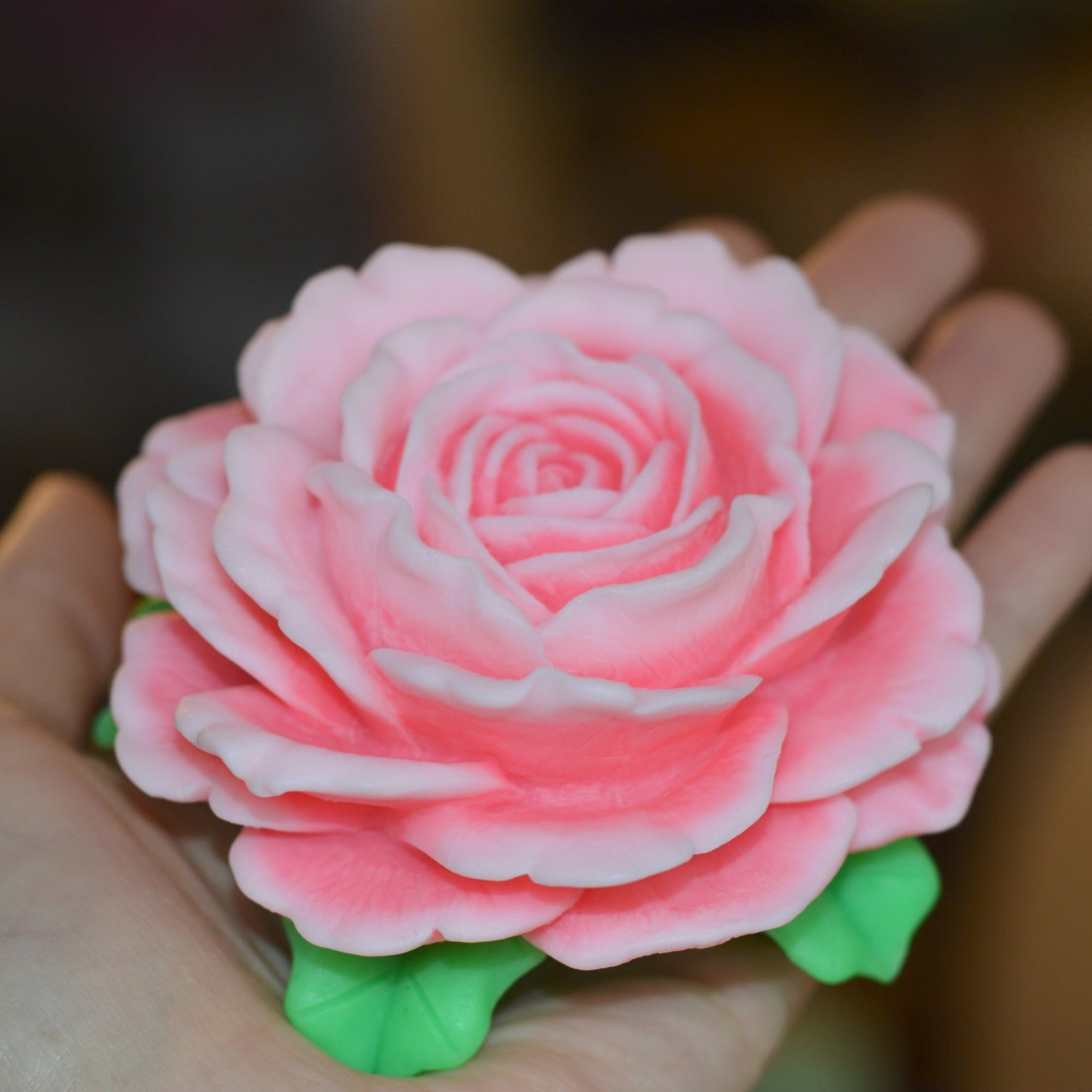 Pink rose-shaped object held in a hand with a blurred background