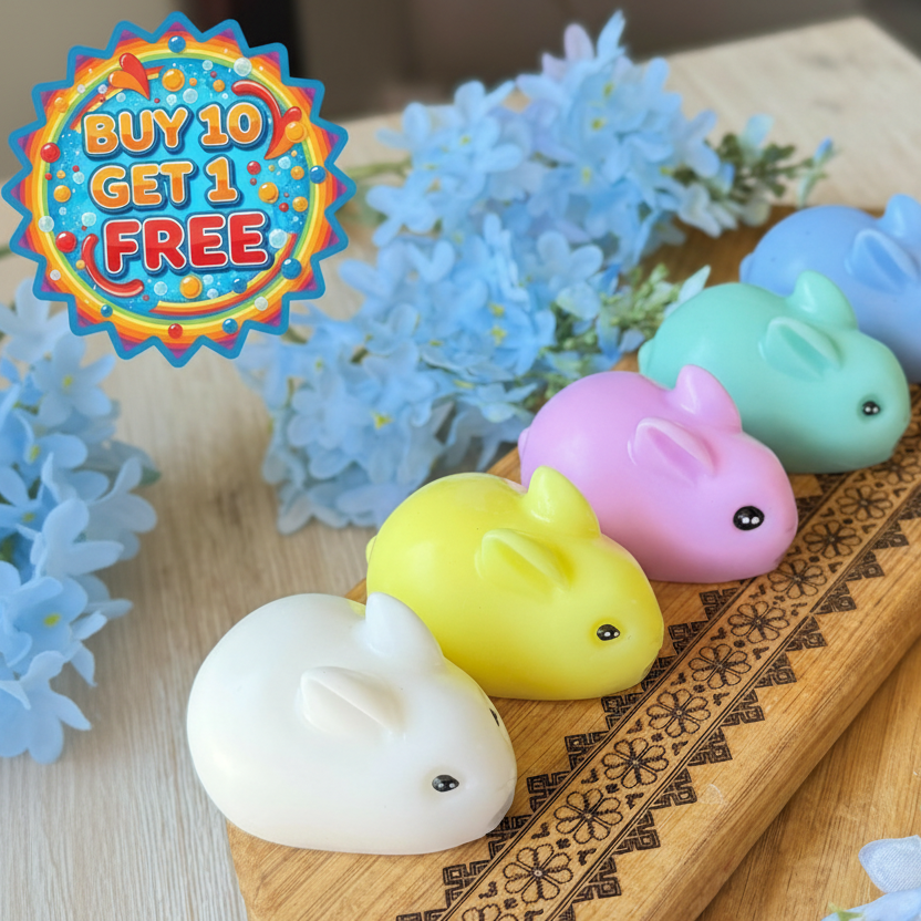 Colorful rabbit-shaped candles on a wooden tray with decorative flowers.
