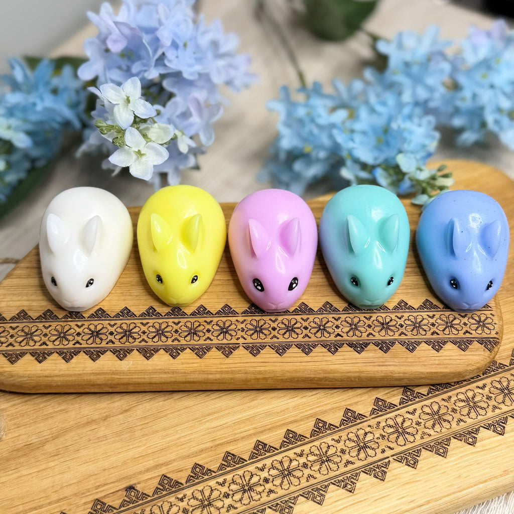 Five colorful rabbit-shaped candies on a wooden tray with floral background