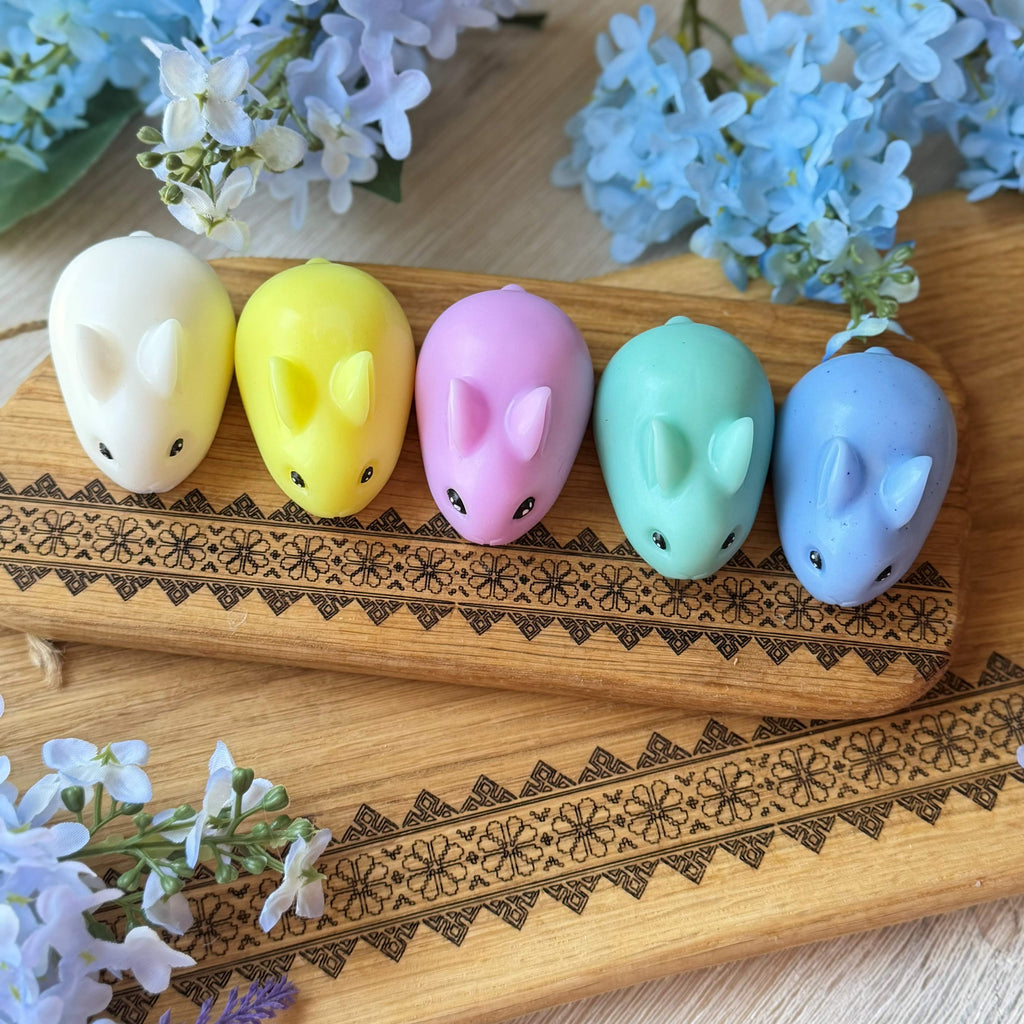 Five colorful animal-shaped candles on a wooden board with floral decorations.
